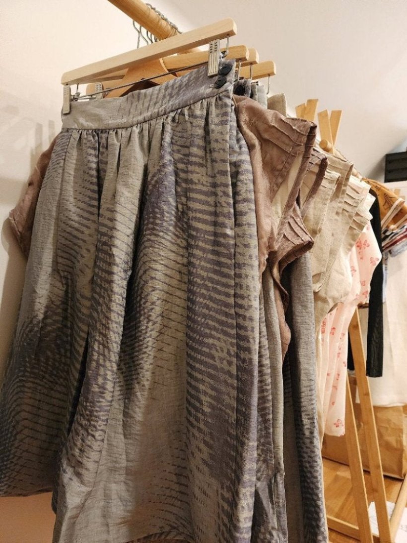 Zero Waste Skirt Gathered Abstract hanging on rack with zero waste tops on wooden coathangers and a wooden rack with a white background. the Australian made skirt has an abstract wave pint and blue and grey coulour palette