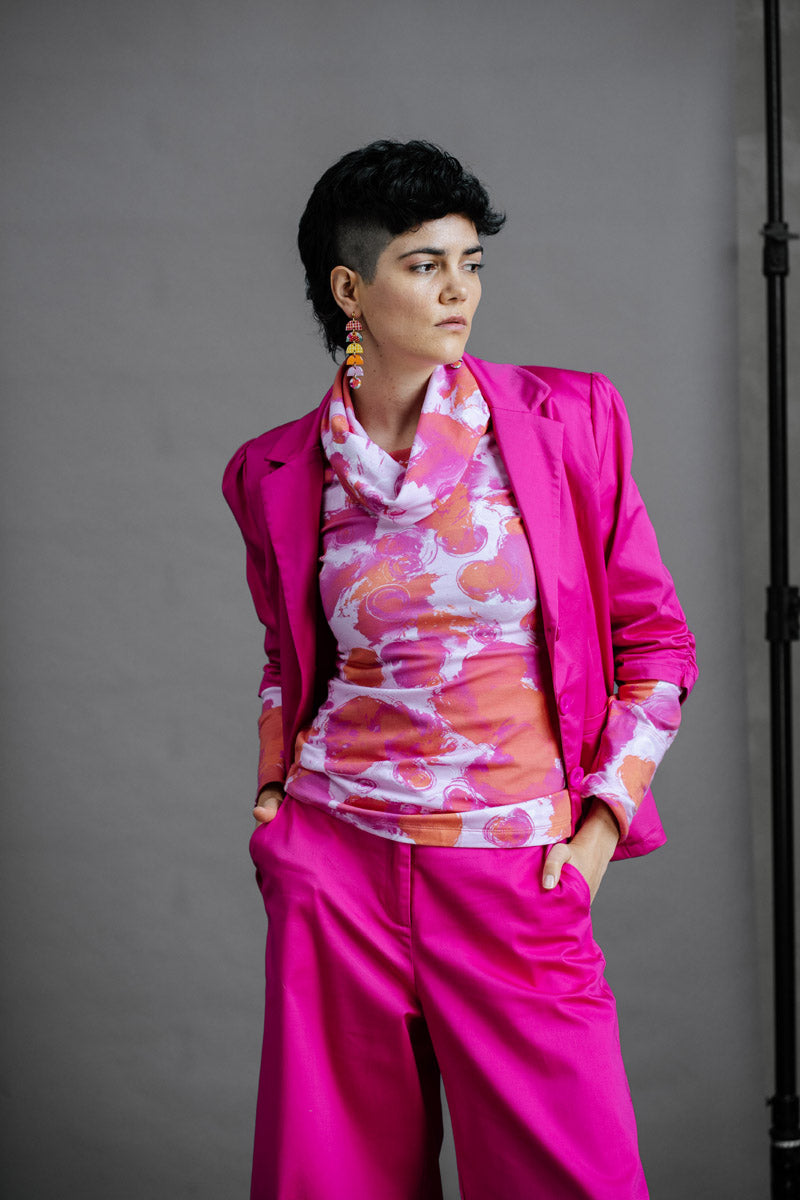 Model wearing the by Audrey and Grace Ruby Jumper in Fairy Floss print, an abstract print of magenta and dusty orange on a pale pink background. This Australian made jumper is styled with a funky thrifted magenta suit.
