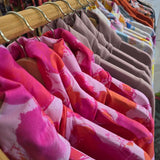A wooden rack can be see on a slight angle from front to back. The ruby jumper Fairy flossis at the front and we can see the folded over cowl turtle neck and shoulder of 5 of these then we can see the lavender jumpers in the ruby jumper style and then some more, getting smaller as the image moves further away
