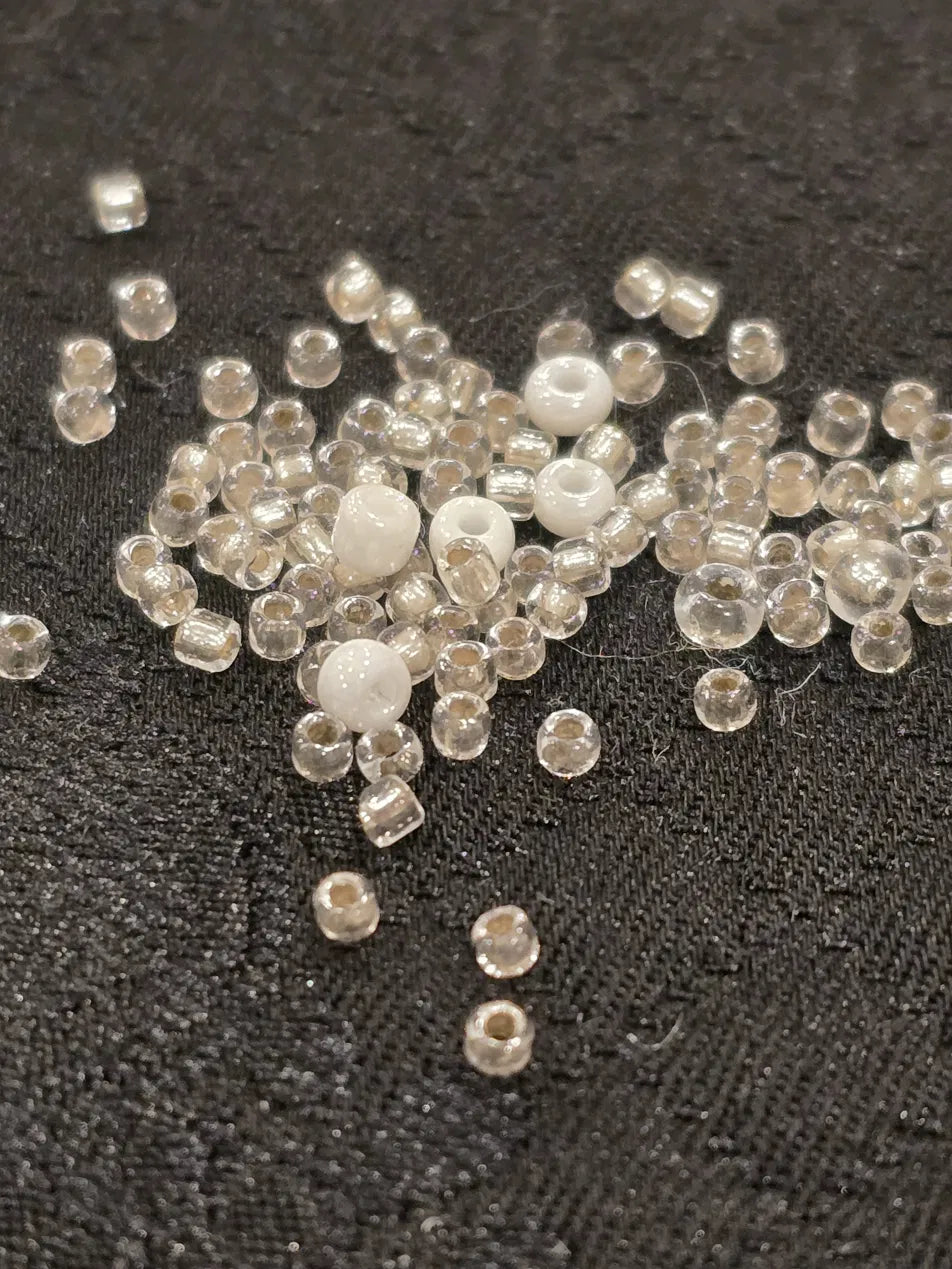 silver and white glass seed beads scattered on a deep black satin wool Japanese Jacquard 