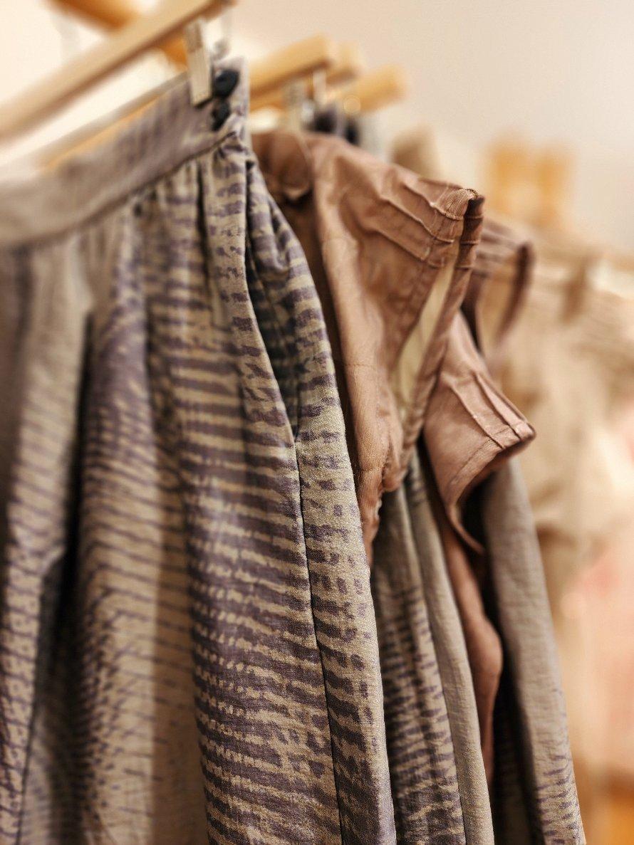 Close-up of zero waste skirts and tops in printed fabrics, hanging neatly on a rack. Ethically made, Australian women’s clothing for gifting.