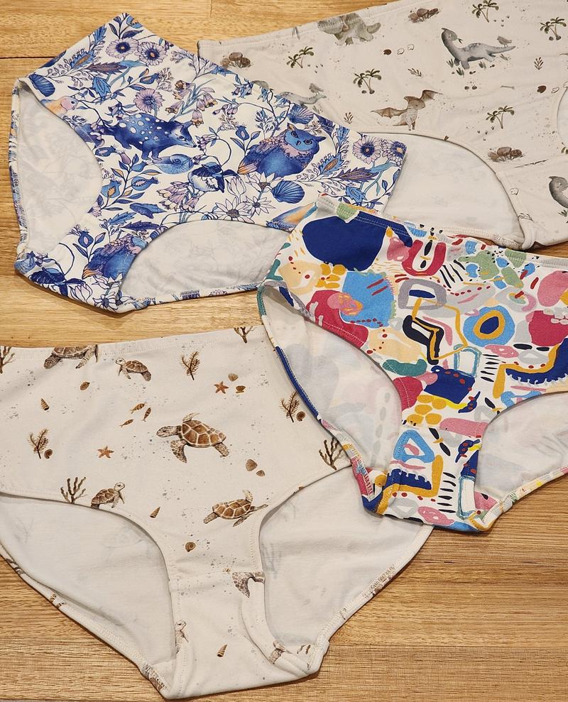 Big Girls Briefs in four different prints laid on a wooden surface.