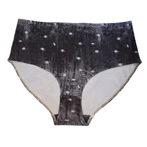 A flat lay of the front of the Night Snow Big Girls briefs on a white background, showing a transitioning black to grey mottled print with white dots that look like large snow flakes, covering the print