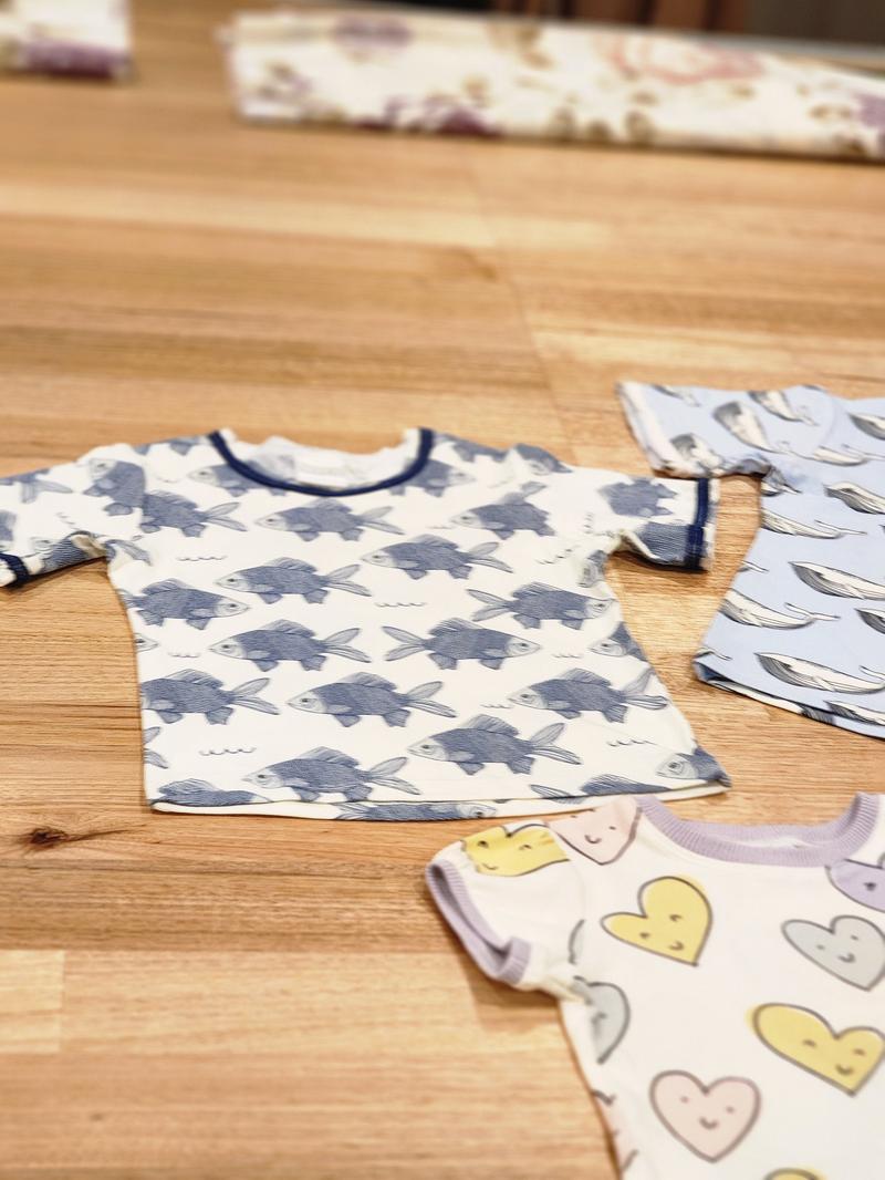 Kids raw edge tee in Fish print, organic cotton — front flat lay with Smiley Hearts and Blue Whales tees