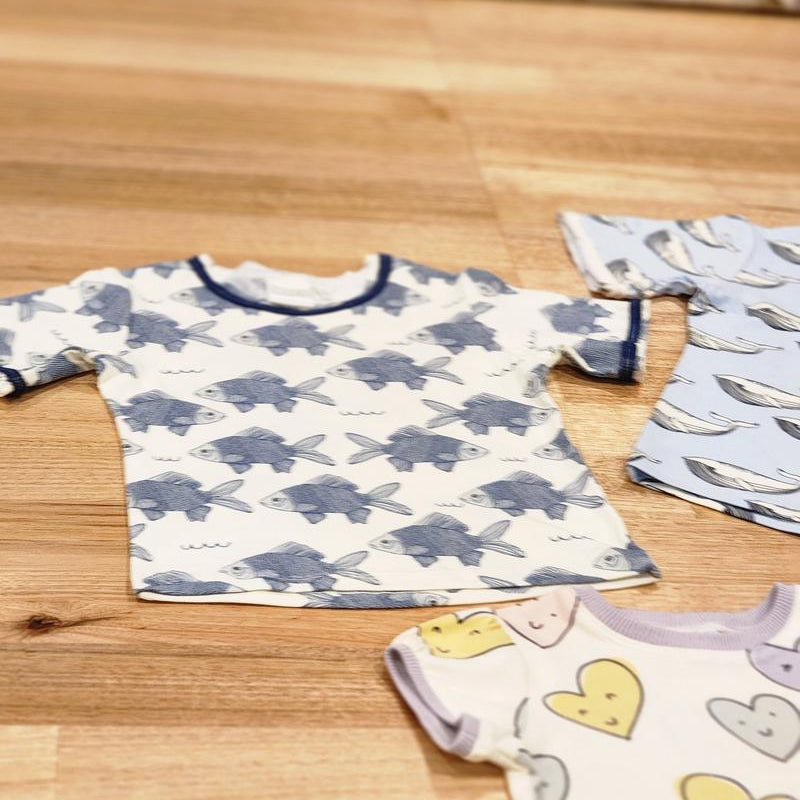 Kids raw edge tee in Fish print, organic cotton — front flat lay with Smiley Hearts and Blue Whales tees