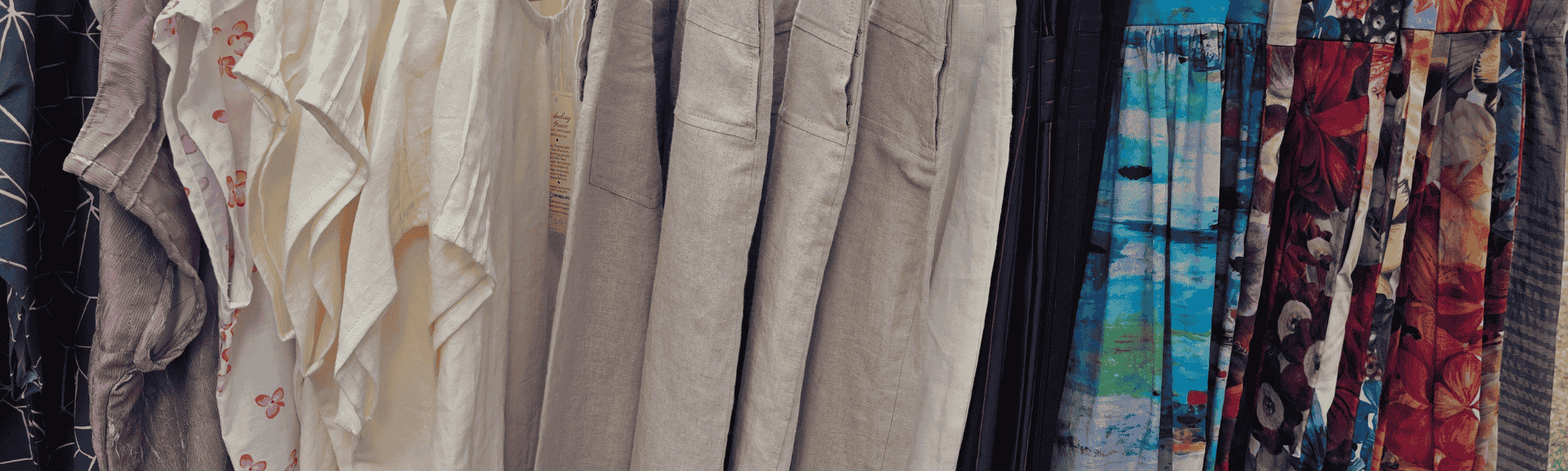 Image of someZero Waste Tops , Yoke trousers in organic linen and Zero Waste skirts hanging on a rack in landscape view.  