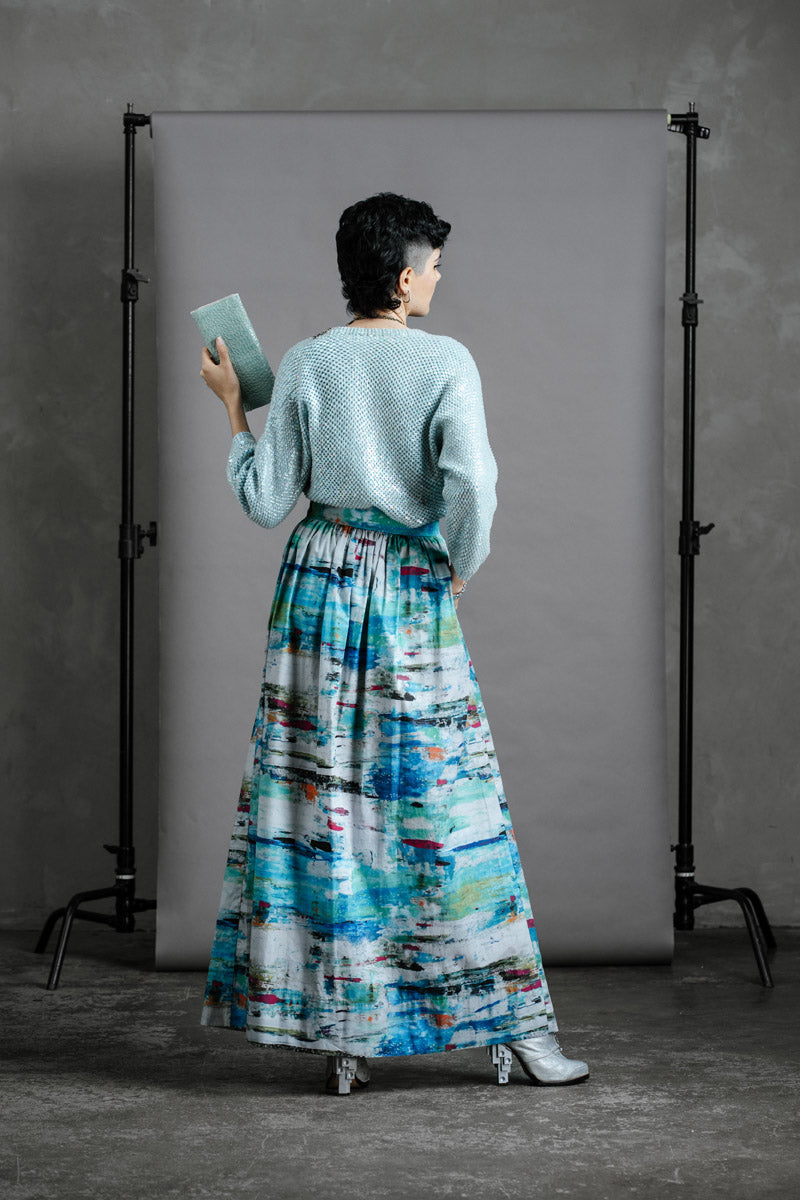Back view of Model wearing the Zero Waste Ocean Skirt styled with vintage sequinned cardigan and holding a pale blue green  thrifted purse