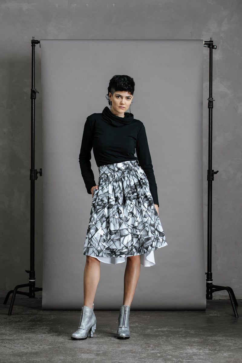 Model wearing Hiding Hares zero waste skirt with black Ruby jumper tucked in and silver ankle boots, hand in side pocket, full length front view