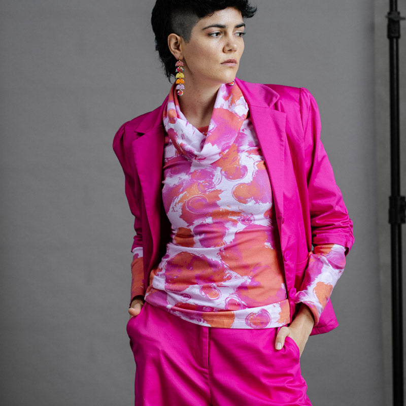 Model wearing the by Audrey and Grace Ruby Jumper in Fairy Floss print, an abstract print of magenta and dusty orange on a pale pink background. This Australian made jumper is styled with a funky thrifted magenta suit.