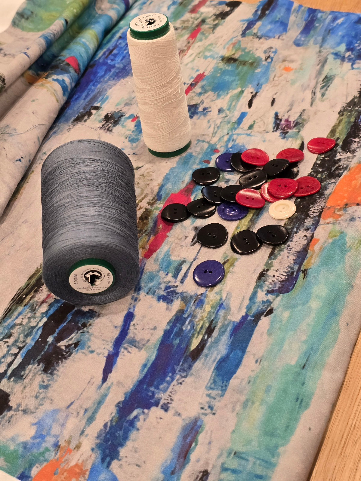 image of organic cotton fabric featuring the abstract ocean print with natural corozo buttons and GOTS certified organic cotton thread.