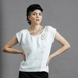 Model wearing the Oyster coloured zero waste top showing featured pin tucks for elegance and shaping and rosette at shoulder.  The models hands are on her hips and she is wearing a pearl chocker to finish of the look of this piece of Australian made women's clothing.