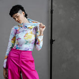 Model in by Audrey & Grace Ruby Jumper in Bubbles print, stretching out the large, cosy turtleneck, paired with thrifted, high waisted bright pink trousers.