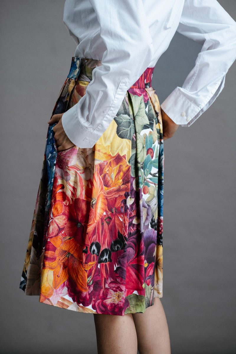 Zero Waste Box Pleat Skirt in Big Bloom, organic cotton — side back view, model has hands in big side pockets and is wearing a white shirt