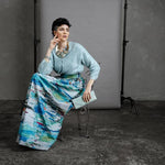 Model sitting on vintage 1950s chair wearing Ocean skirt, cross-legged with chin resting on hand