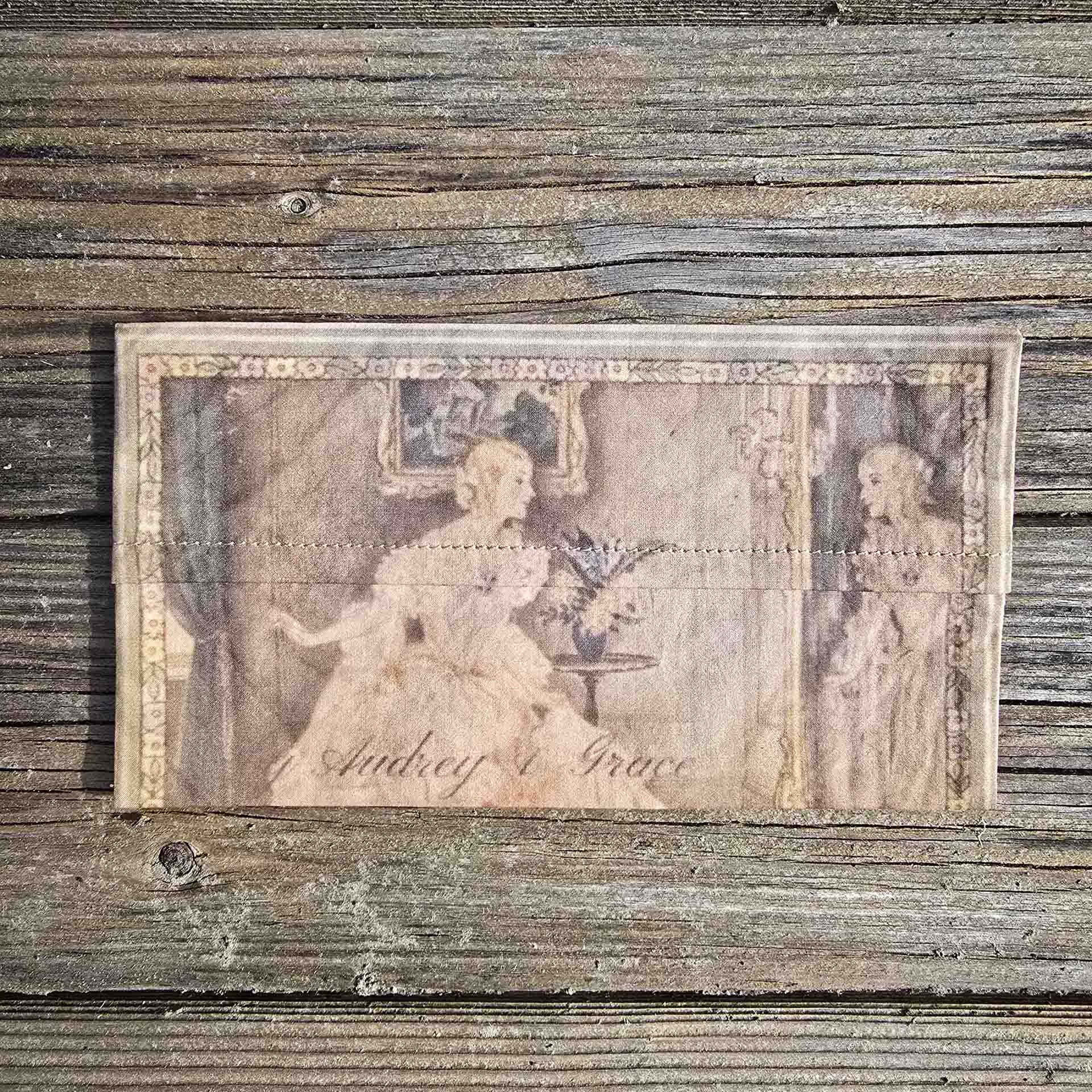 A delicate rectangle pouch, with the image of a lady wearing a period dress with corset and crinoline, admiring herself in a gilded mirror.