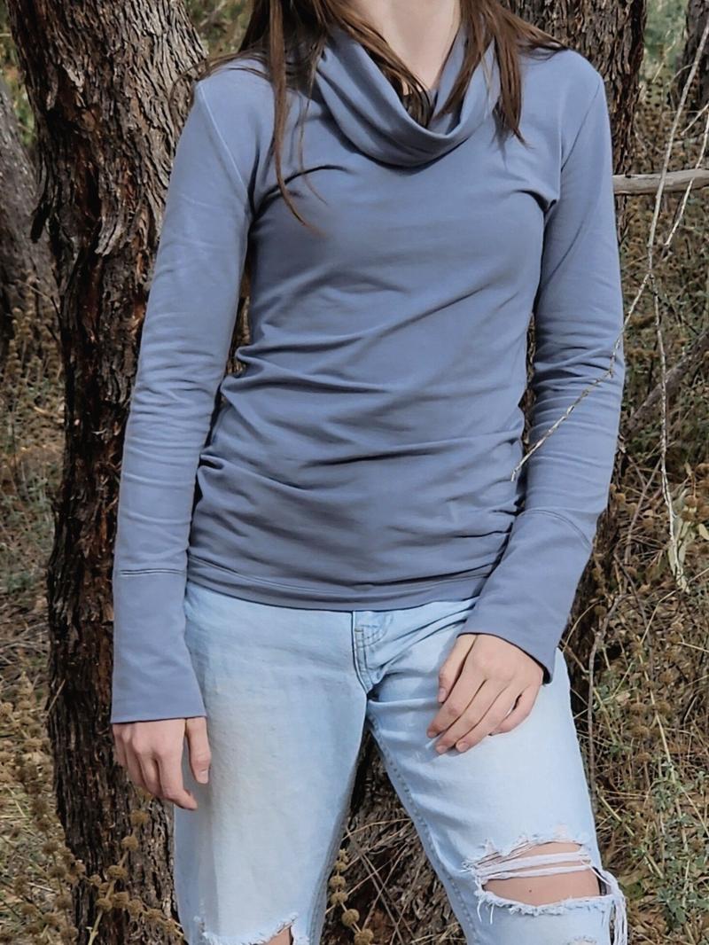 The Ruby Jumper in Storm, a blue grey colour, with large cowl neck, Australian Women's Jumpers made from Australian cotton — model standing front on with tree behind her, cropped