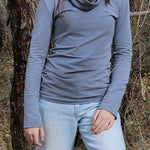 The Ruby Jumper in Storm, a blue grey colour, with large cowl neck, Australian Women's Jumpers made from Australian cotton — model standing front on with tree behind her, cropped