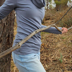 The Ruby Jumper in Storm, a blue grey colour, with large cowl neck, Australian Women's Jumpers made from Australian cotton — model side on walking through nature, cropped