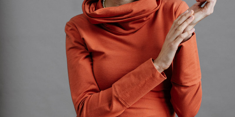 The Ruby Jumper in Terracotta, sustainable and ethical women's jumpers made from Australian cotton — front view with model's hands together and to the side, cropped