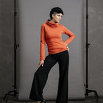 The Ruby Jumper in Terracotta, sustainable and ethical women's jumpers made from Australian cotton — front view with model's hand on hip and knee bent to the side, other hand on knee