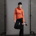 The Ruby Jumper in Terracotta, sustainable and ethical women's jumpers made from Australian cotton — front view, model holding foot with leg bent and foot at hip