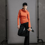The Ruby Jumper in Terracotta, sustainable and ethical women's jumpers made from Australian cotton — front view, model holding foot with leg bent and foot at hip