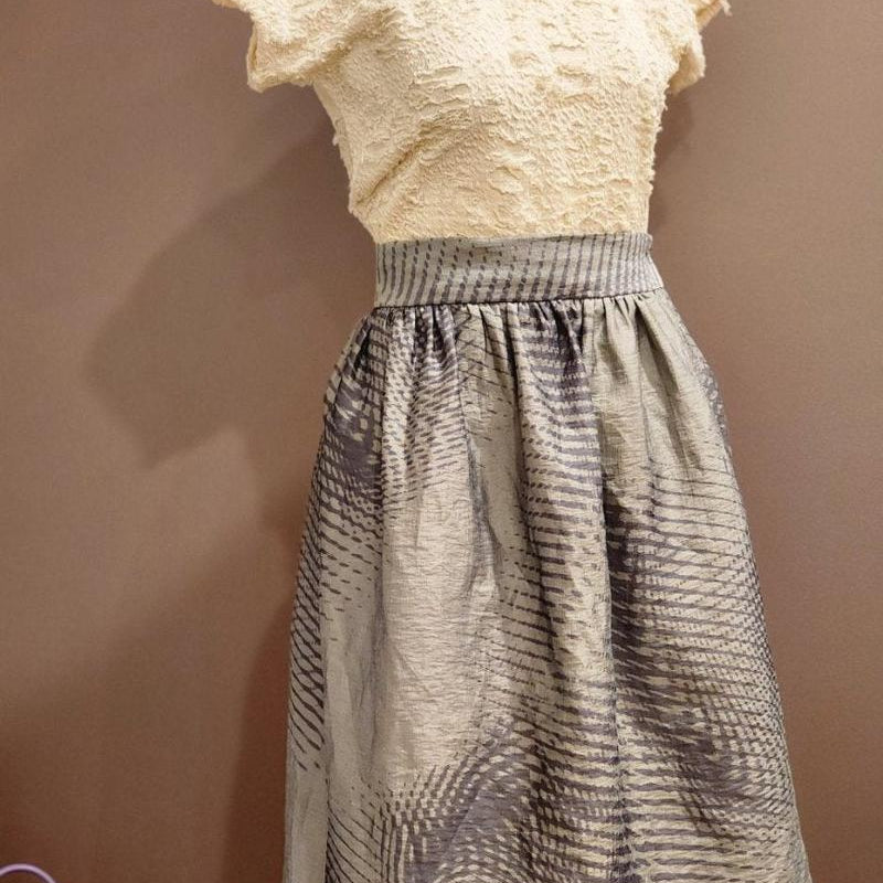 by Audrey and Grace zero waste skirt with an abstract wave print worn over a cream top and modelled on a mannequin. It is fitted at the waist and is a tailored skirt in a classic style with timeless design. the skirt sots just below knee height.